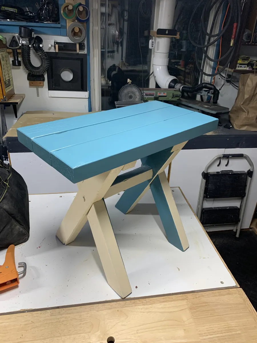 Small painted wooden chair with crossed legs and a blue seat, in the Oakleaf shop in Baltimore